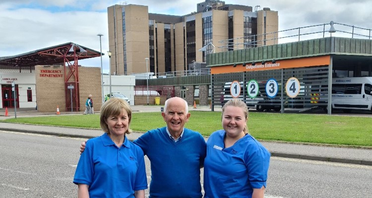 a family of three NHS employees in front of Raigmore Hospital