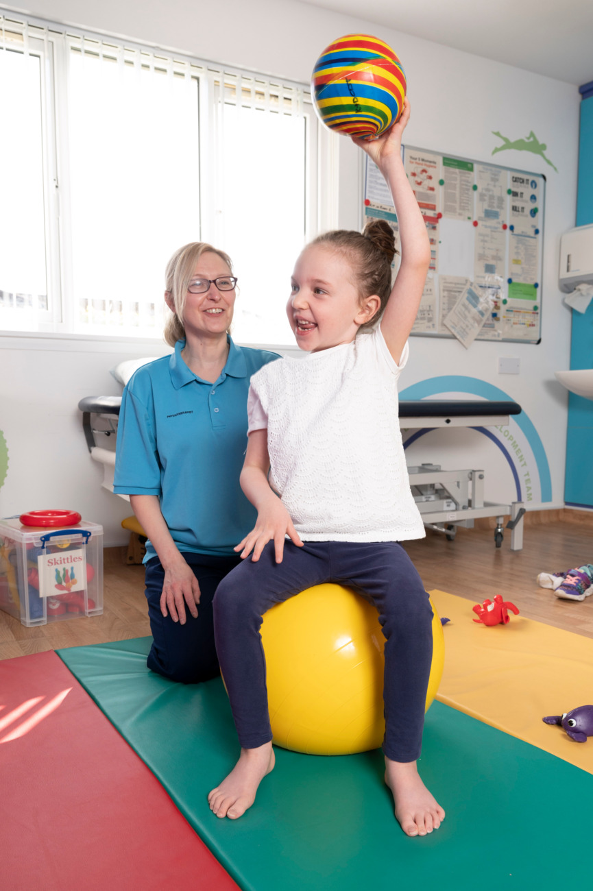 Physiotherapist With Child Raising A Ball Over Her Head