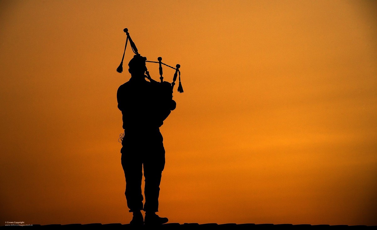 silhouette of a Highland Piper from the Armed Forces against an orange sky