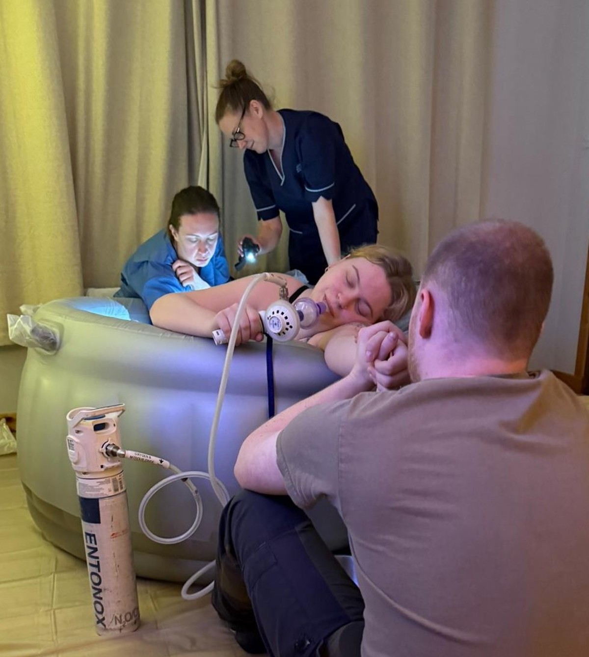 Woman Giving Birth In An Inflatable Birth Pool At Home Using Entonox