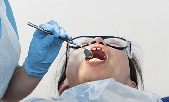 Dentist Examining Patient Teeth With Mirror