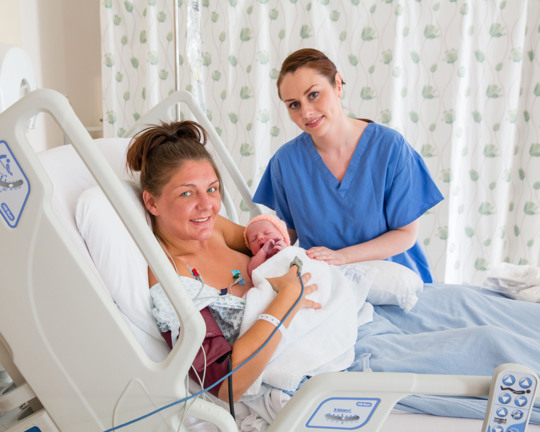 Baby With Mother And Midwife In Maternity Unit