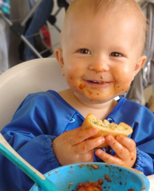 Baby In High Chair Eating Solid Food
