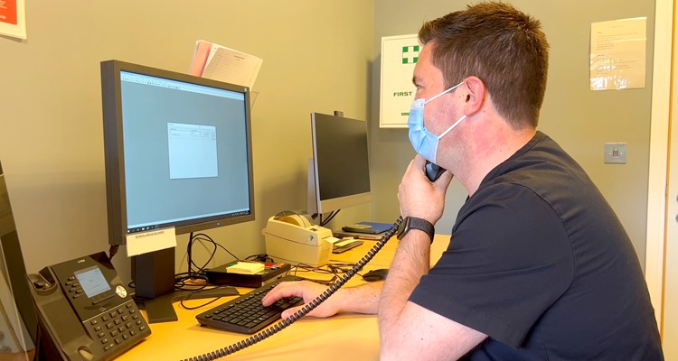 a telephonist wearing a hygiene mask in front of a PC